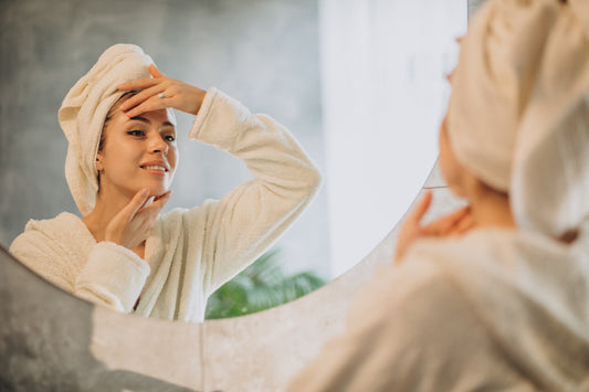 Femme en peignoir appliquant sa skincare routine femme devant un miroir